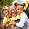 Senior woman cuddling her two granddaughters outdoors